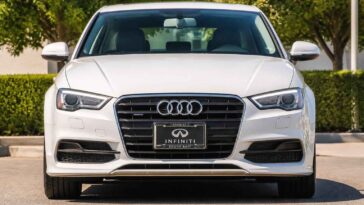 Biały sedan Audi sfotografowany z przodu na parkingu, z widocznym grillem i reflektorami