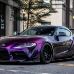 Fioletowa Toyota Supra zaparkowana na miejskiej ulicy wśród wysokich budynków
