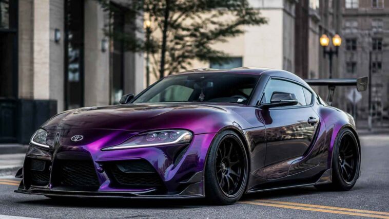 Fioletowa Toyota Supra zaparkowana na miejskiej ulicy wśród wysokich budynków