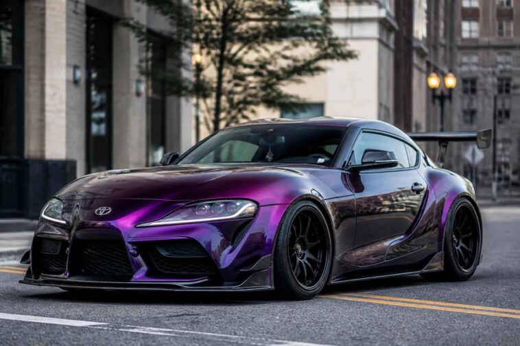 Fioletowa Toyota Supra zaparkowana na miejskiej ulicy wśród wysokich budynków